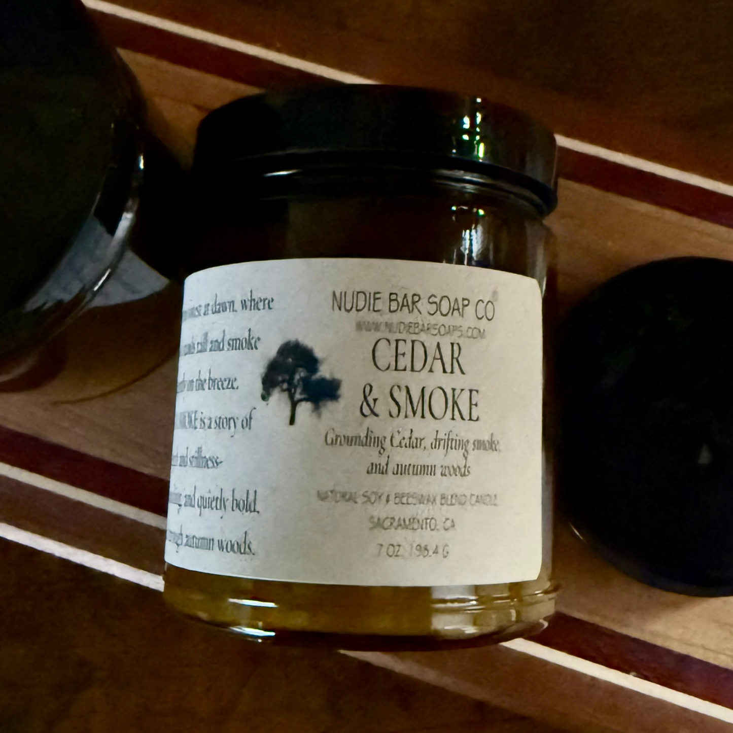 Jar of candle labeled 'Cedar & Smoke' on a wooden surface