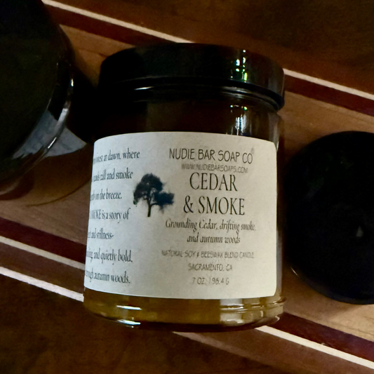 Jar of candle labeled 'Cedar & Smoke' on a wooden surface